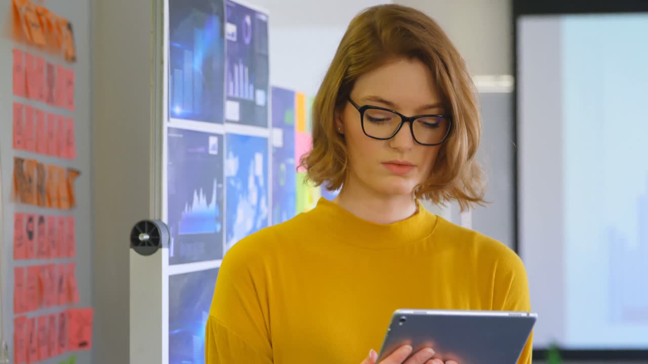 vista frontal de una joven ejecutiva que trabaja en una tableta digital en una oficina moderna 4k