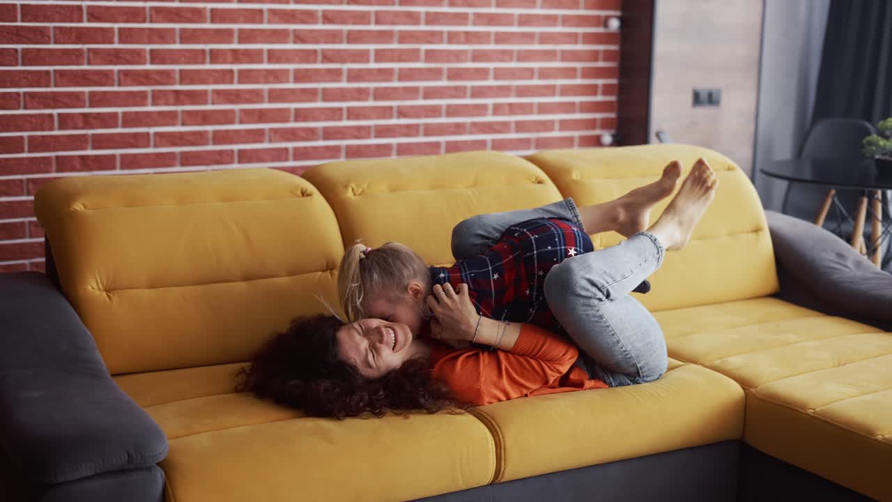 madre levantando a la niña en el aire en sus tobillos en casa, uniéndose