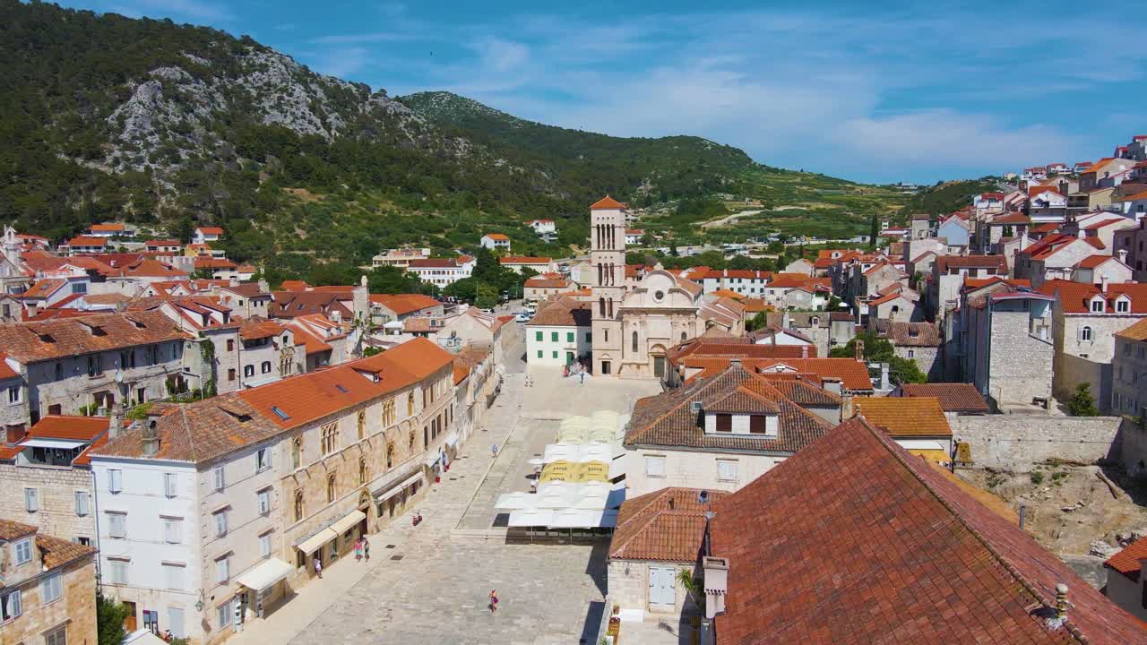 View of a coastal town with many houses with red roofs, surrounded by the sea and mountains with yachts  in marina bay and Bell tower