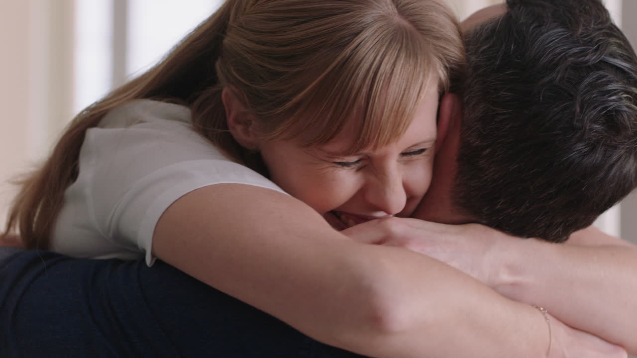 coppia felice che si abbraccia donna eccitata che abbraccia il fidanzato che condivide buone notizie che gode di una relazione romantica a casa