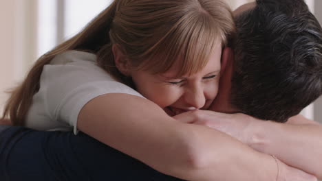 happy couple hugging excited woman embracing boyfriend sharing good news enjoying romantic relationship at home