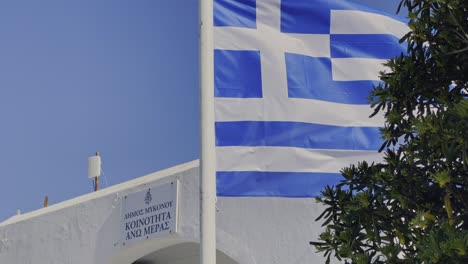 Greek-flag-waving-in-Ano-Mera-village-in-Mykonos,-Greece