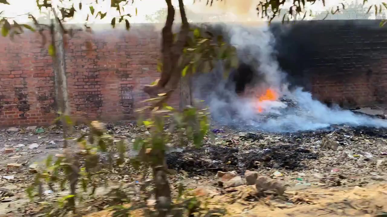 Plastic and garbage burning causing severe local air pollution alongside brick wall in dhaka city