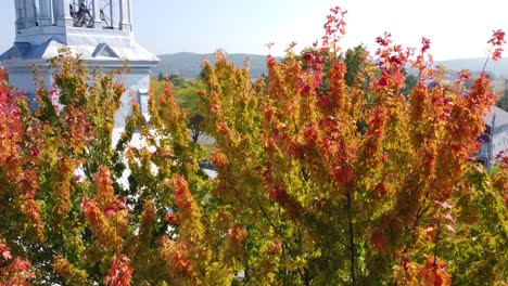 rotating shot of beautiful colorful trees on an autumnal beside a church on a bright sunny day