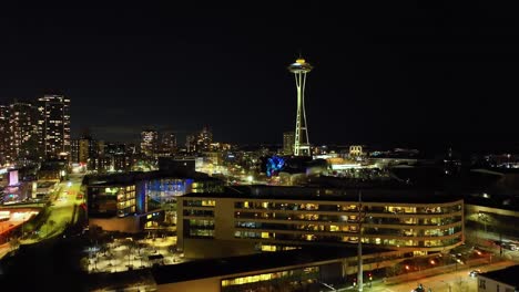 space needle to reveal downtown seattle cityscape illuminated night skyline, aerial view rising up on city