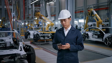 engineer using smartphone in modern car manufacturing plant