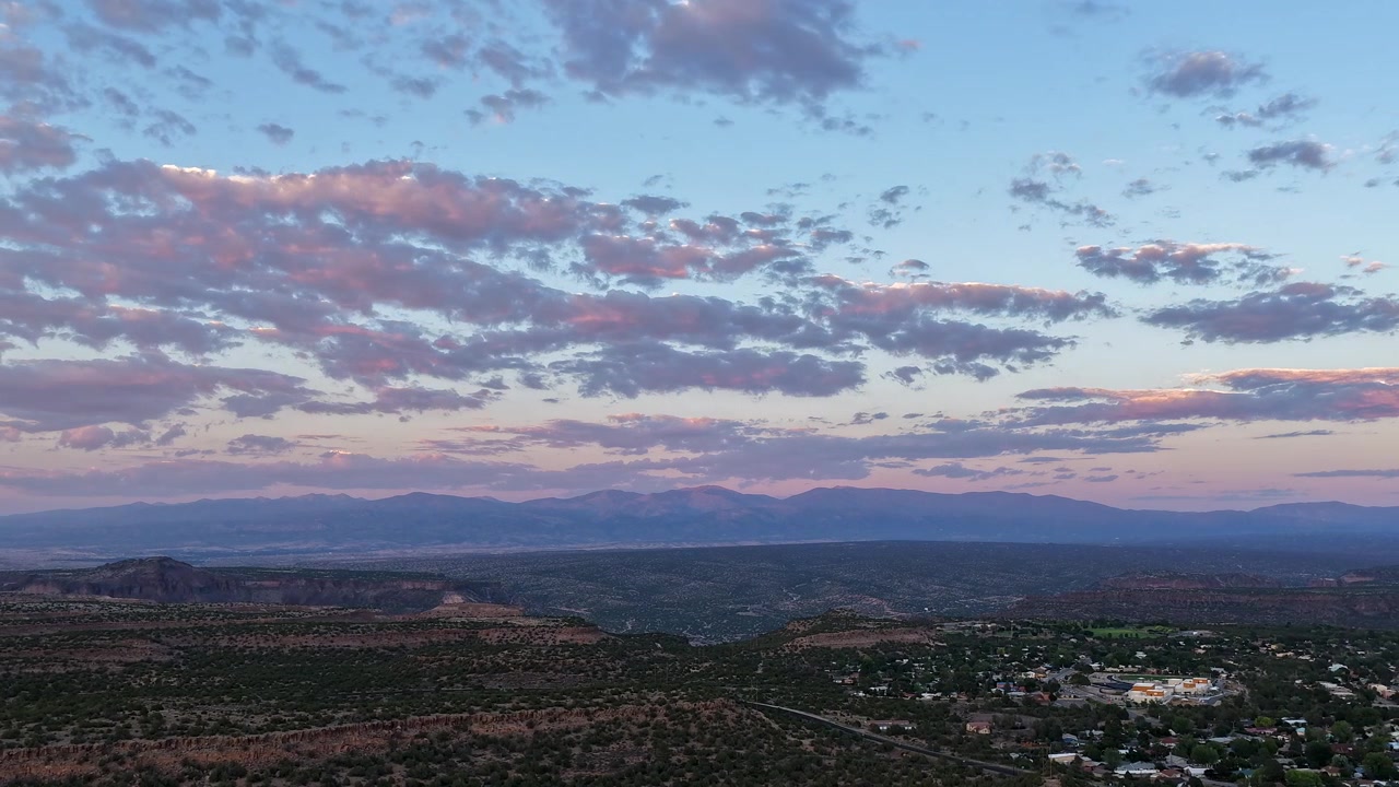 4K luft-hyperlapse svævende over mesa-byen White Rock, New Mexico. Bløde pastelfarver ved daggry oplyser de skiftende morgenskyer over den fjerne sydlige Rocky Mountain-kæde
