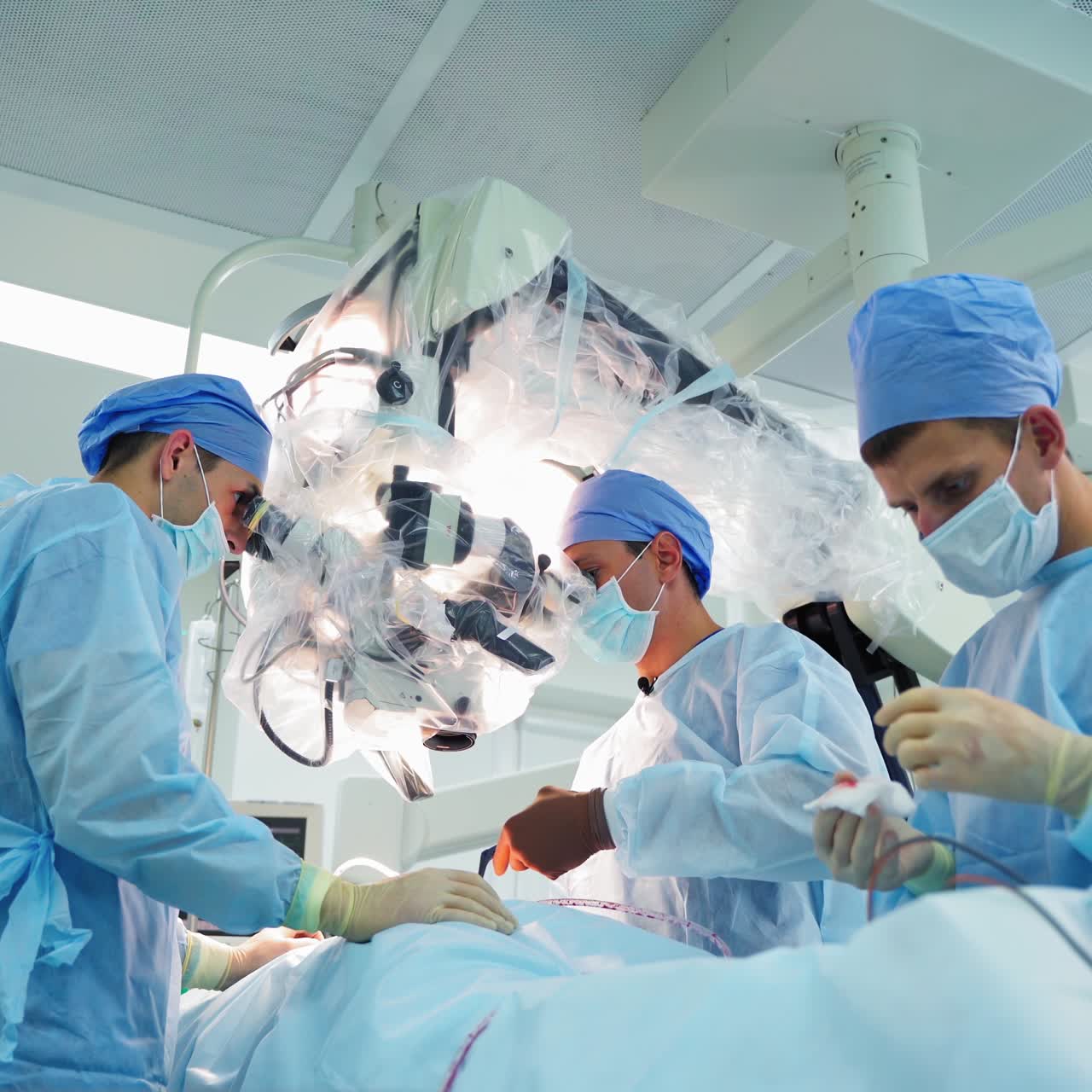 Surgical process with microscope. Doctors and male assistant conduct a surgery using modern medical equipment in clinic. Innovation in medicine.