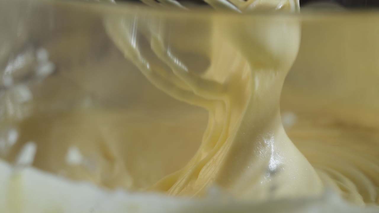 View through a glass bowl of a person stirring a tiramisu dough