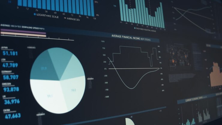 Finger points to graphics, graphs and data on a computer screen in a dark room
