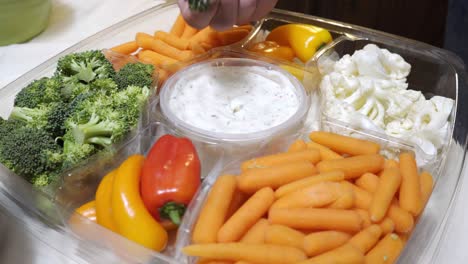 a hand grabs a piece of broccoli from a mixed vegetable platter in 4k