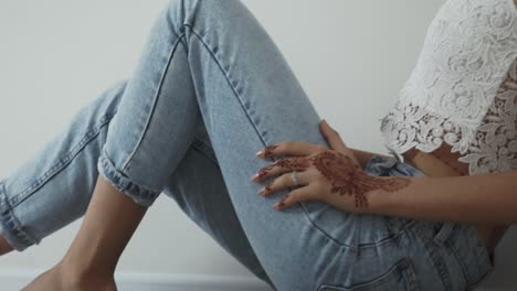 mujer sentada en vaqueros con tatuaje de henna