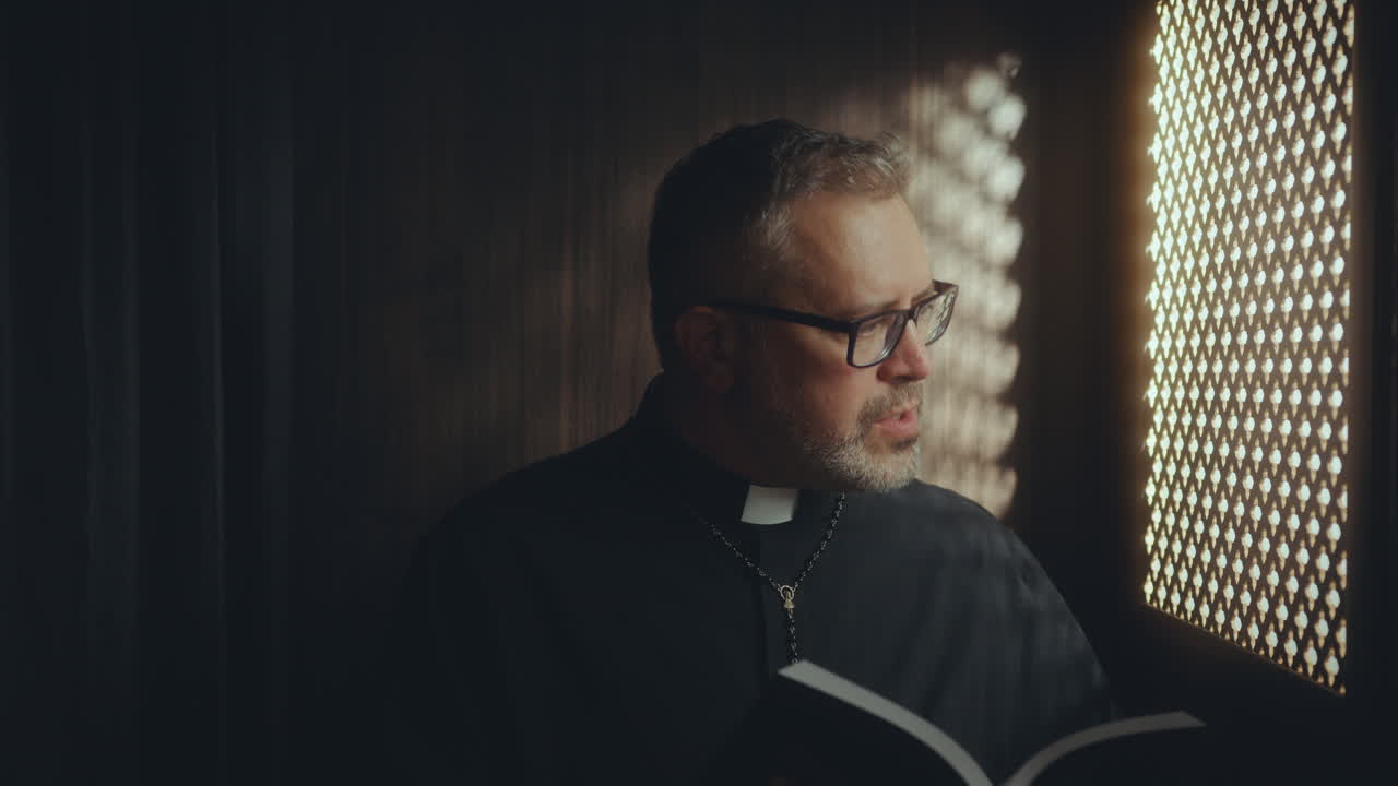 Priest Sitting in Confessional and Reading Bible