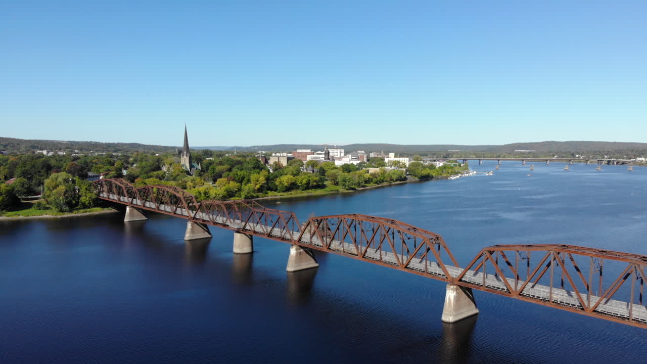 AERIAL: Tilting Up While Flying Toward Downtown Fredericton. Walking Bridge In Foreground.