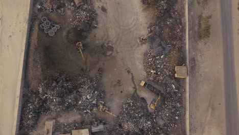 Scrapyard-with-excavators-and-dump-trucks-birds-eye-view