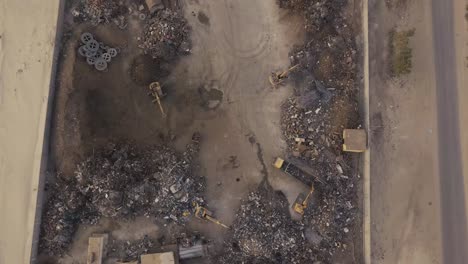 scrapyard with excavators and dump trucks birds eye view