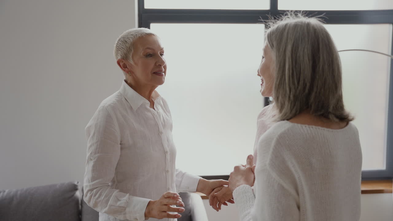 거실에서 이야기하고 웃는 쾌활한 고위 여자 친구 그룹