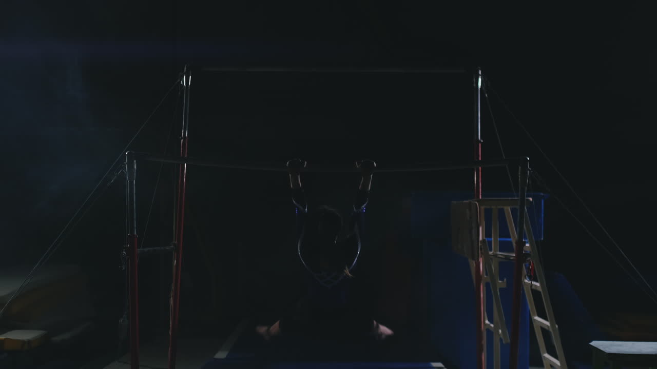 en cámara lenta en el humo chica acróbata en la barra transversal realiza rotación y salto con un golpe. competiciones en gimnasia.