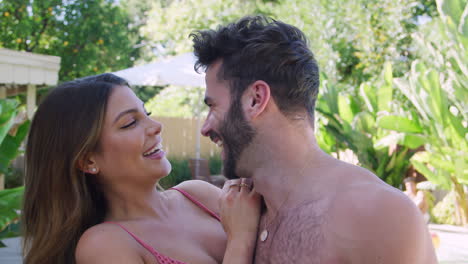 retrato de una pareja romántica hispana al aire libre con amigos disfrutando de una fiesta en la piscina de verano