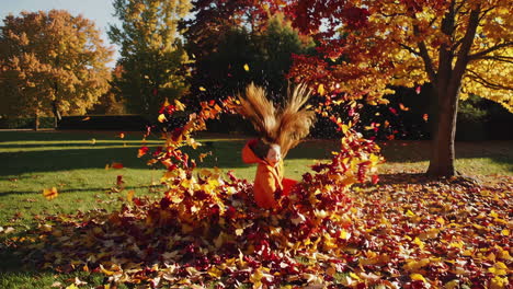 young girl joyfully playing and throwing autumn leaves in a park