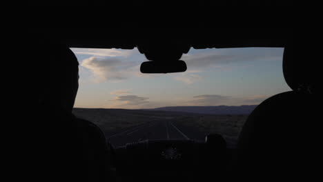 Silhouette-Eines-Mannes,-Der-Bei-Sonnenuntergang-Auf-Einem-Roadtrip-Die-Wüstenstraße-Entlang-Fährt