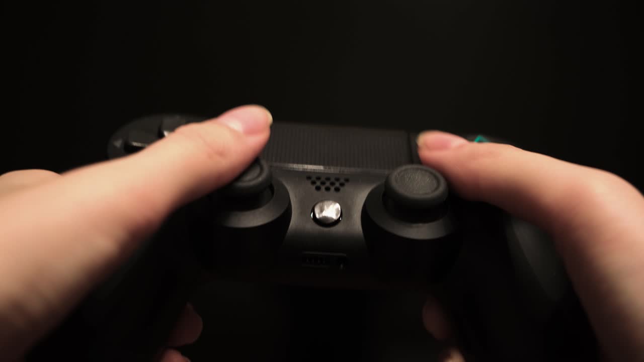 Hands holding a black Playstation controller