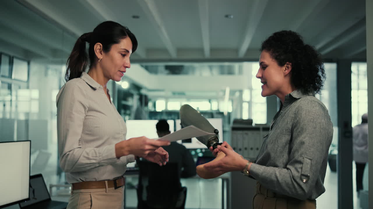 dos mujeres ingenieras discuten un diseño de pierna protésica en una oficina