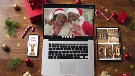 african american senior couple on video call on laptop, with smartphone, tablet and decorations