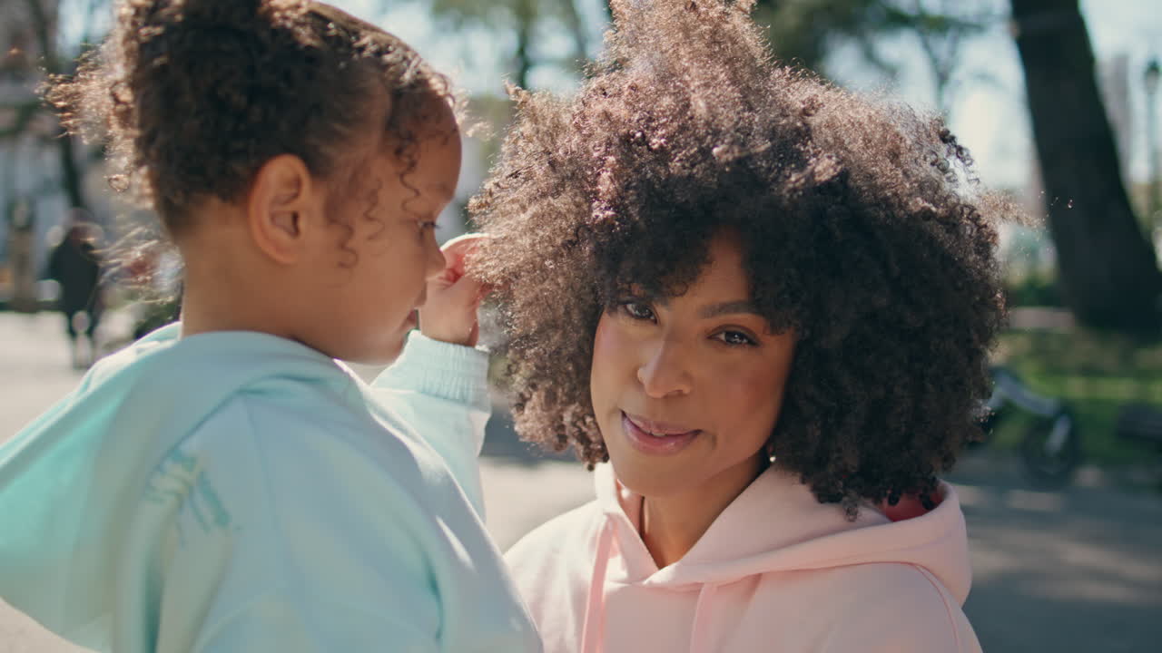 mujer rizada hija disfrutando del tiempo juntos en el parque soleado de cerca. amor familiar