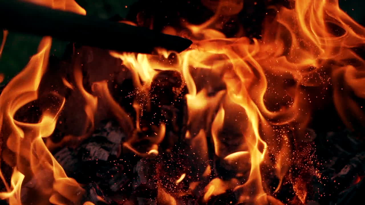Falò. Ceppi che bruciano in fiamme arancioni. Un bel fuoco brucia intensamente. Le braci del fuoco si innalzano. Movimento lento.