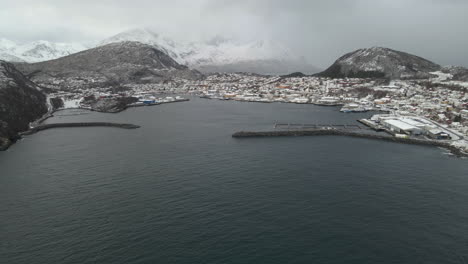 aerial approach - harbour at skjervoy village, nestled under snowy mountains, norway