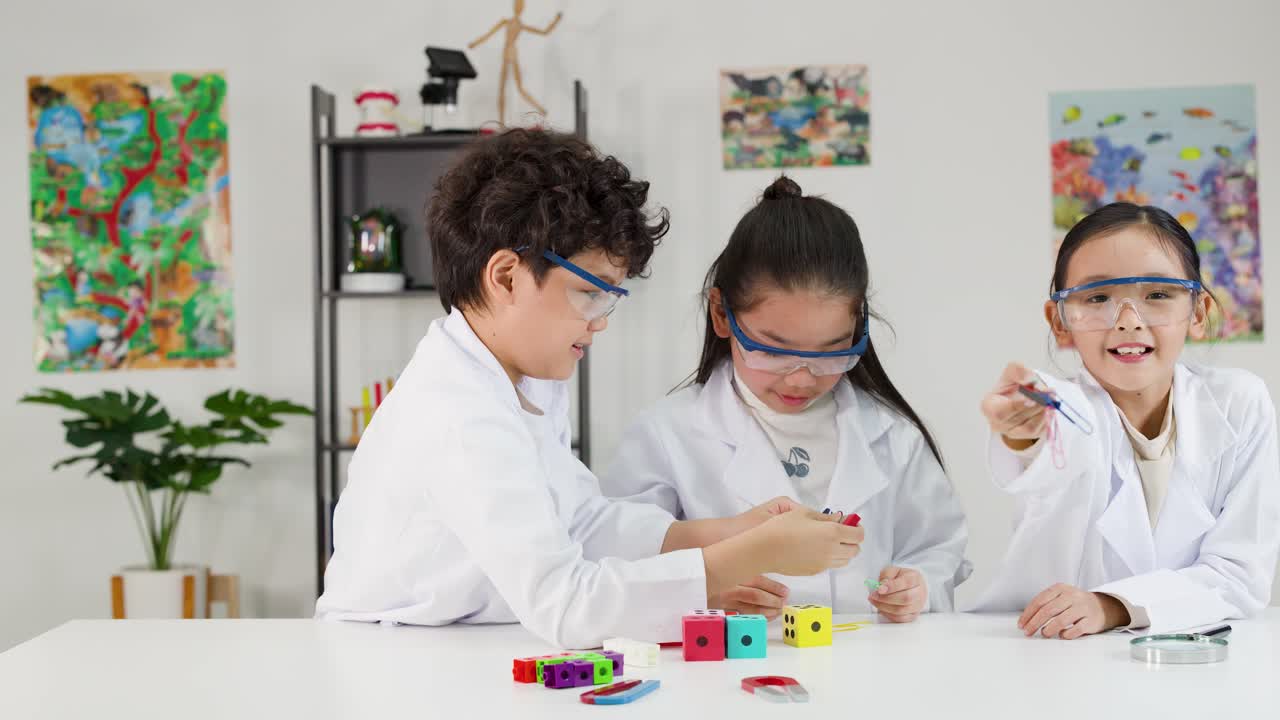 Alakoulun oppilaat laboratoriotakeissa ja suojalaseissa tutkivat magnetismia käyttäen värikkäitä magneetteja luokkahuoneessa.