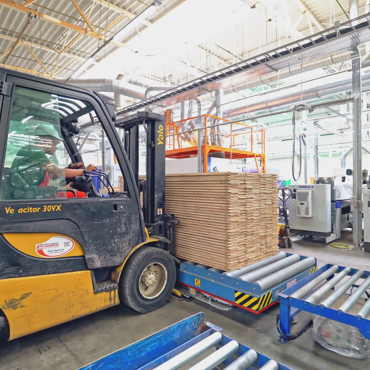 An electric loader puts on the metal pallet a pile of parquet boards under the client's order in the warehouse.