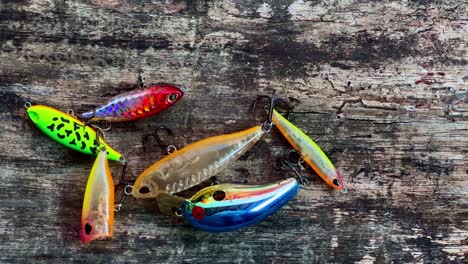 Different-colors-and-shapes-fishing-lures-for-fishing-on-worn-wooden-plank