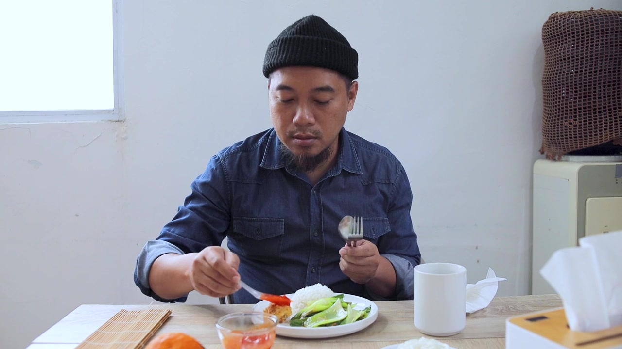 Man cleaning cutlery with tissue before eating meal at wooden table