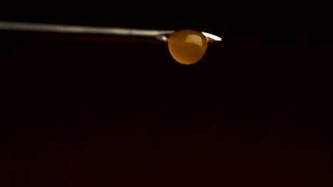 orange liquid droplet on syringe needle