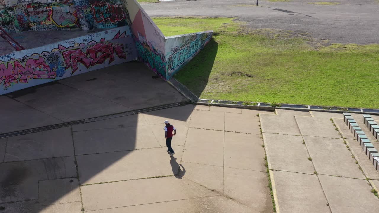 Man playing fronton tennis on a graffitied wall, public park, modern urban amphitheater