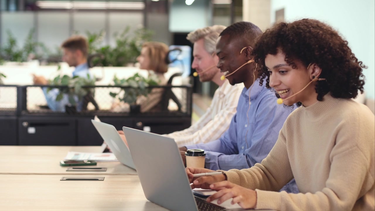 Diverse Customer Service Team Working on Laptops with Headsets in Modern Office