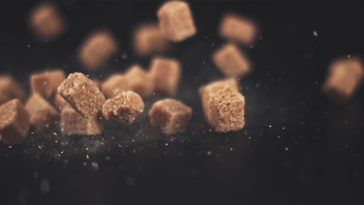 Slow Motion of Brown Sugar Cubes Dropping onto a Black Surface