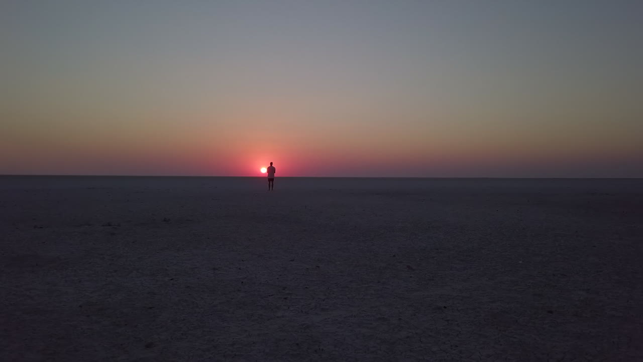 antena de carro bajo del hombre mirando la puesta de sol dorada en una sal plana