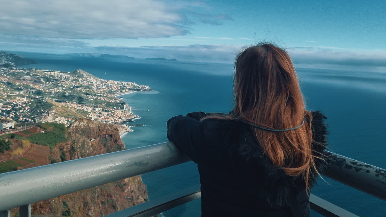 Frau blickt vom Cabo Girao Skywalk in Madeira, Portugal, auf das Meer und die Landschaft