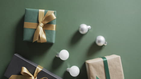 video of christmas presents and baubles with copy space on green background