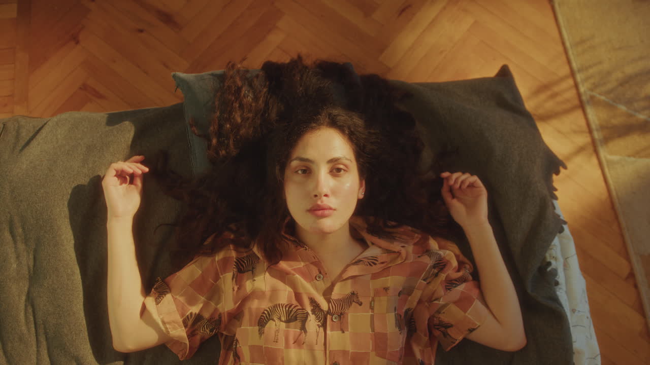 빛이 비치는 방에서 침대에 누워있는 젊은 아름다운 여성의 초상화