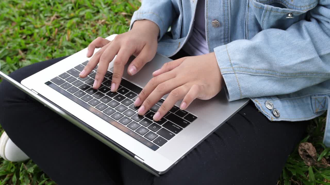 mujer escribiendo en una computadora portátil al aire libre