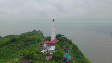 Revele-Una-Foto-De-Un-Faro-Blanco-En-La-Cima-De-La-Colina-Que-Bordea-El-Mar---Playa-Baron,-Indonesia