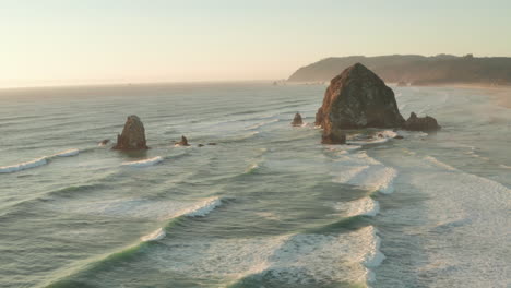 wide circling aerial shot of haystack rock at sunset