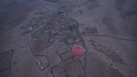 hot air balloon fly above small town in morocco, handheld view from above