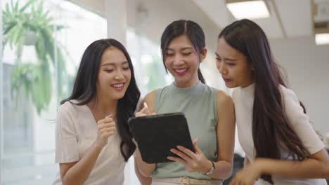 asian female colleagues looking at tablets together at the office