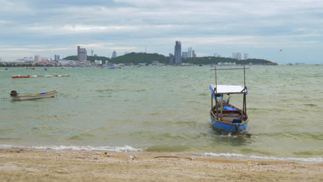 a sailboat and a motorboat floating near the seashore anchored paragliding can be seen at a distance