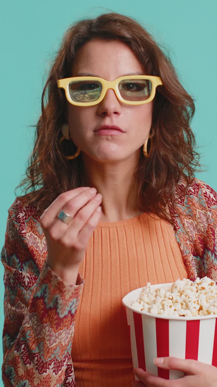Donna con occhiali 3D che mangia popcorn e guarda online un film, una partita sportiva o una serie TV interessante